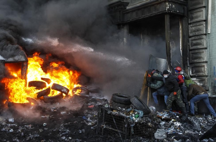 fot. Wasilij Fedosenko / Reuters / 23 stycznia 2014  Kijów, Ukraina  Protestanci opowiadający się za przyłączeniem Ukrainy do Unii Europejskiej chronią się przed armatkami wodnymi skierowanymi w ich kierunku przez oddziały policyjne.